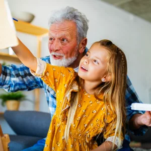 grandfather paints side by side with his granddaughter