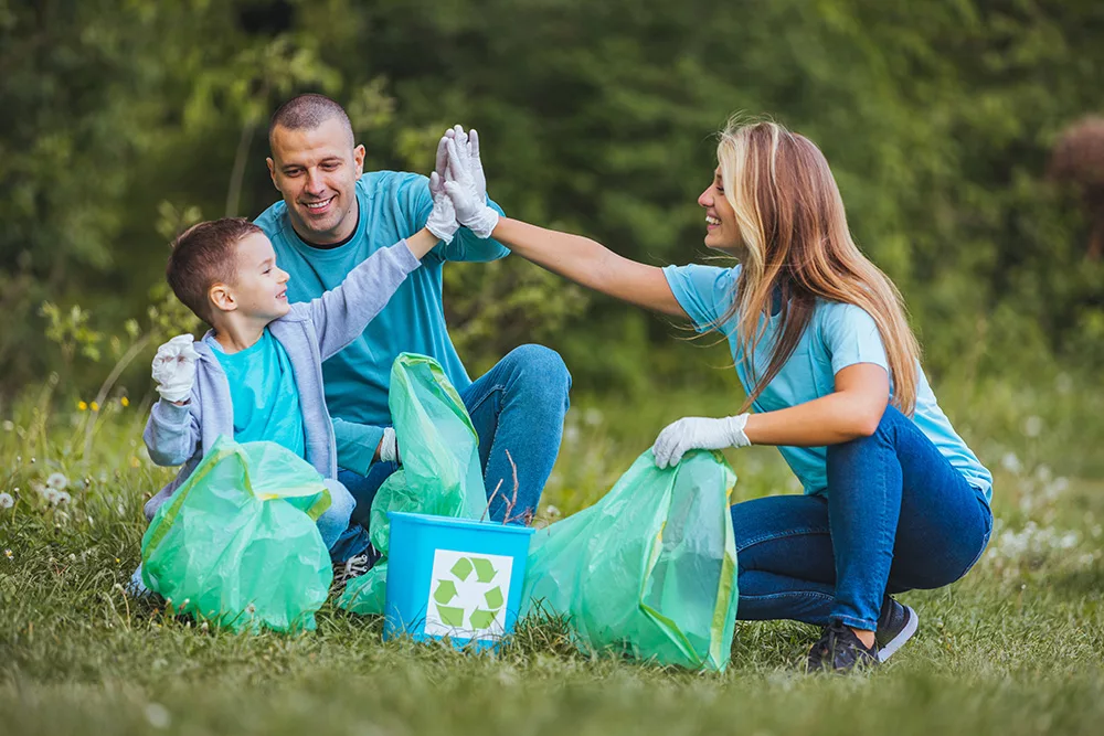 A young toddler picking up litter and plastic waste in a park with his parents.