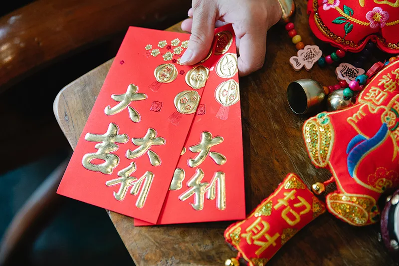 Una mano sostiene dos sobres rojos de la suerte, que tradicionalmente se regalan a los niños durante el Año Nuevo Lunar.
