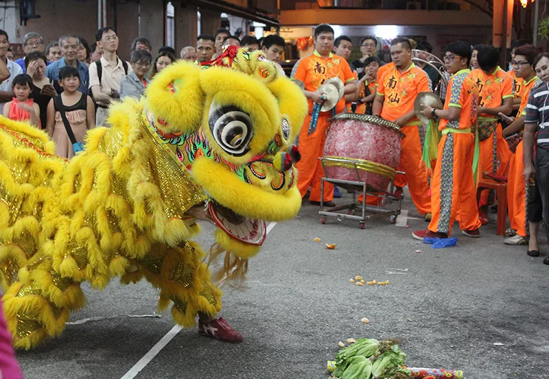 Desfile del Año Nuevo Lunar ante un templo chino con danza del dragón y tambores