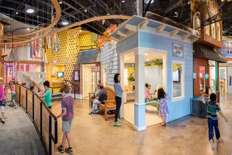 A panoramic view of the interior of the Children's Museum of Sonoma County featuring children and parents playing with interactive exhibits.