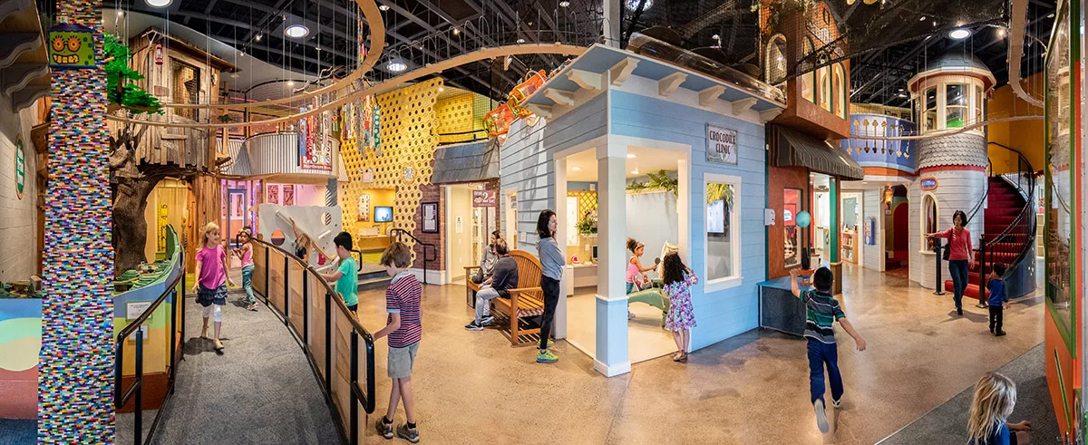 A panoramic view of the interior of the Children's Museum of Sonoma County featuring children and parents playing with interactive exhibits.