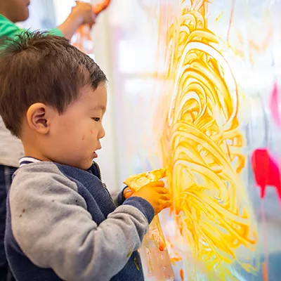 child painting on window with fingers