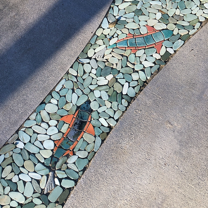 Un hermoso mosaico fluvial de aguas azules impresionantes con peces de vivos colores naranjas y verdes, realizado por la artista local del condado de Sonoma, Angelica Duckett, e instalado en el Museo Infantil del Condado de Sonoma.