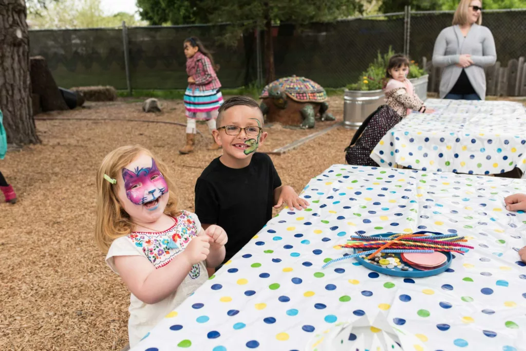 2 niños sentados uno al lado del otro en una mesa de picnic para una fiesta de cumpleaños en el museo infantil's