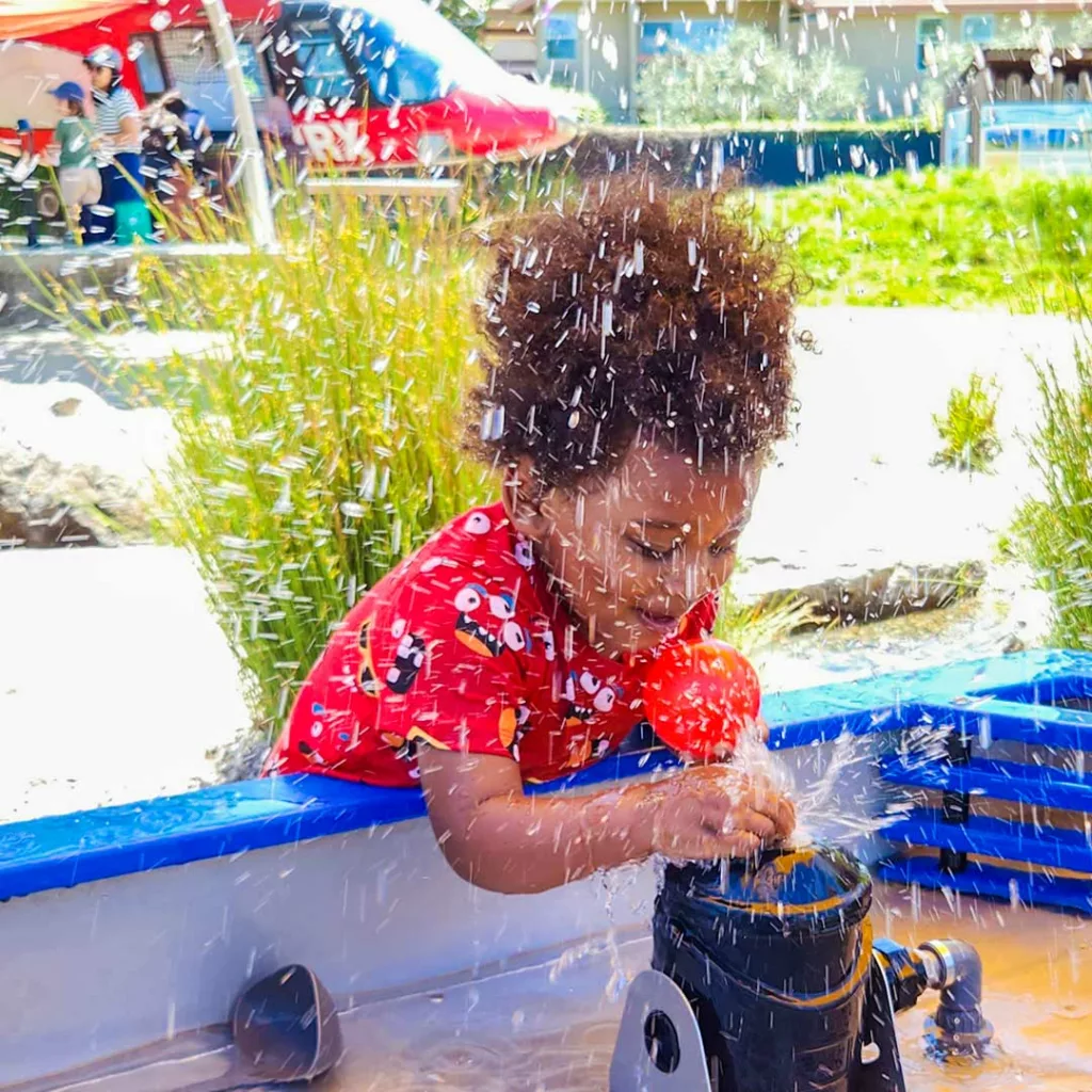 little girl playing with the new waterways exhibit at the children's museum