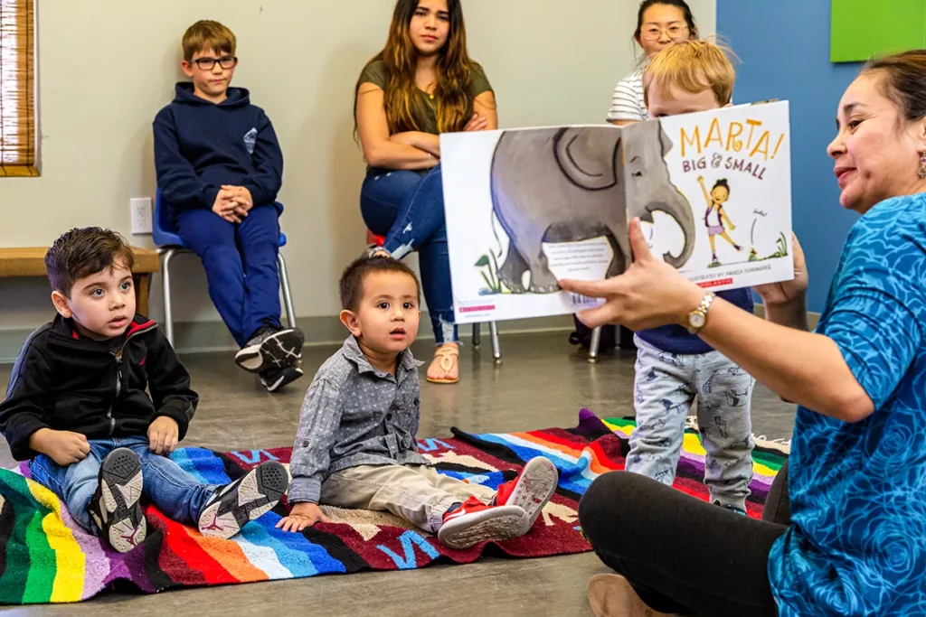 Guadalupe from Colors of Spanish reading a bilingual children's picture book to a group of children during the Tiempo del Cuento program at the Children's Museum of Sonoma County.