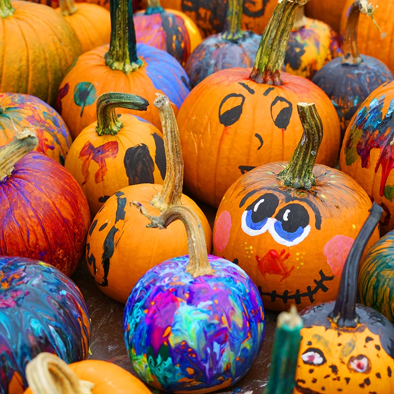 A bunch of pumpkins painted by children during a Halloween art activity for kids. (Pumpkin carving alternative for toddlers)