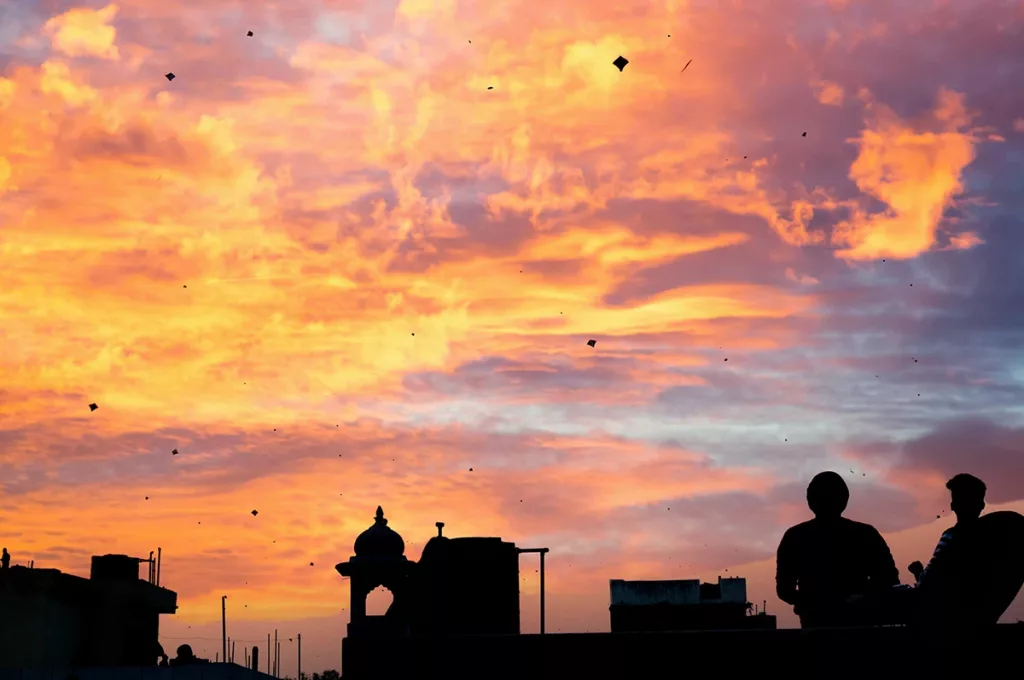 Una puesta de sol brillante y colorida con decenas de cometas dibujando la silueta del cielo para celebrar el festival anual Makar Sankranti en la India.