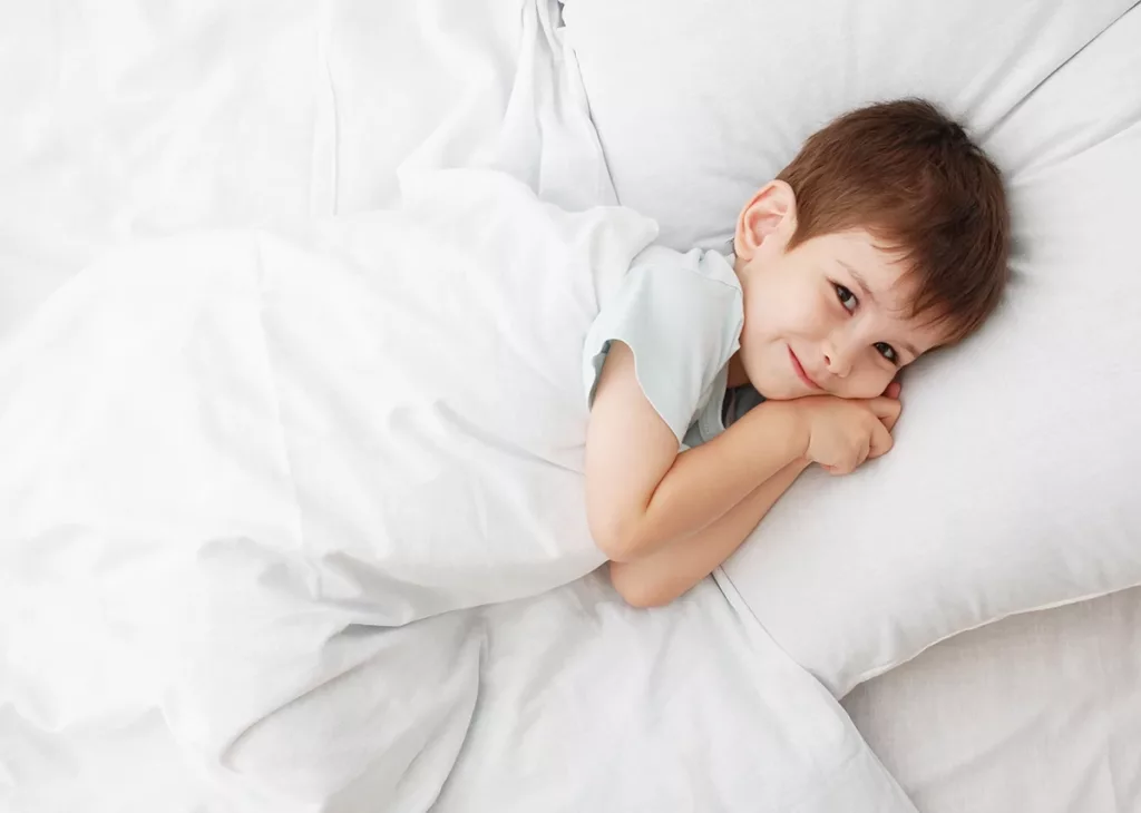 A young boy between that ages of 4 to 6 years old, laying down for nap time.