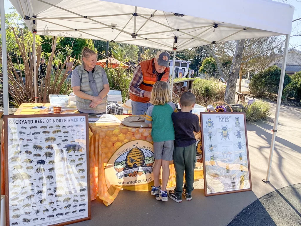 Dos apicultores de la Asociación de Apicultores del Condado de Sonoma y dos niños en el Museo Infantil del Condado de Sonoma durante el programa educativo mensual para niños Meet a Beekeeper.