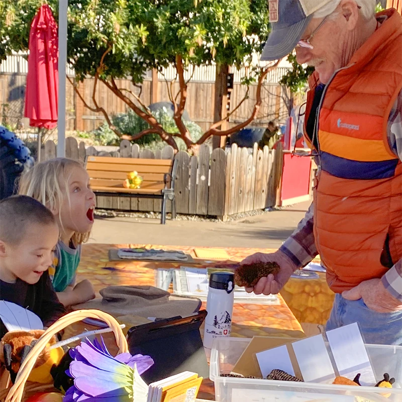 Un apicultor de la Asociación de Apicultores del Condado de Sonoma y dos niños en el Museo Infantil del Condado de Sonoma durante el programa educativo mensual para niños Meet a Beekeeper.
