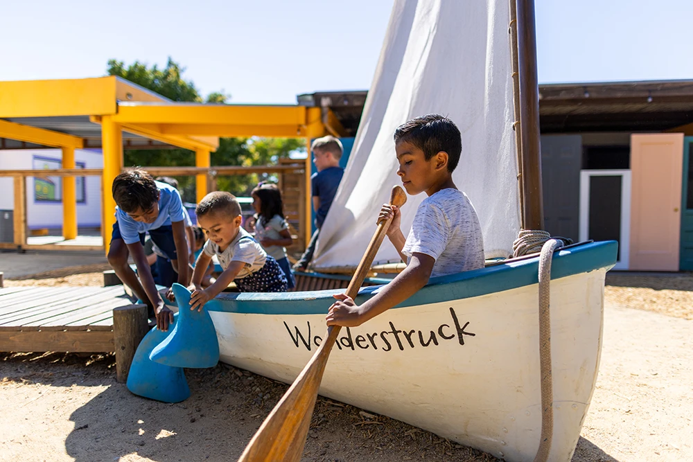 Four children playing in a real sail boat named the "Wonderstruck" in Mary's Garden.