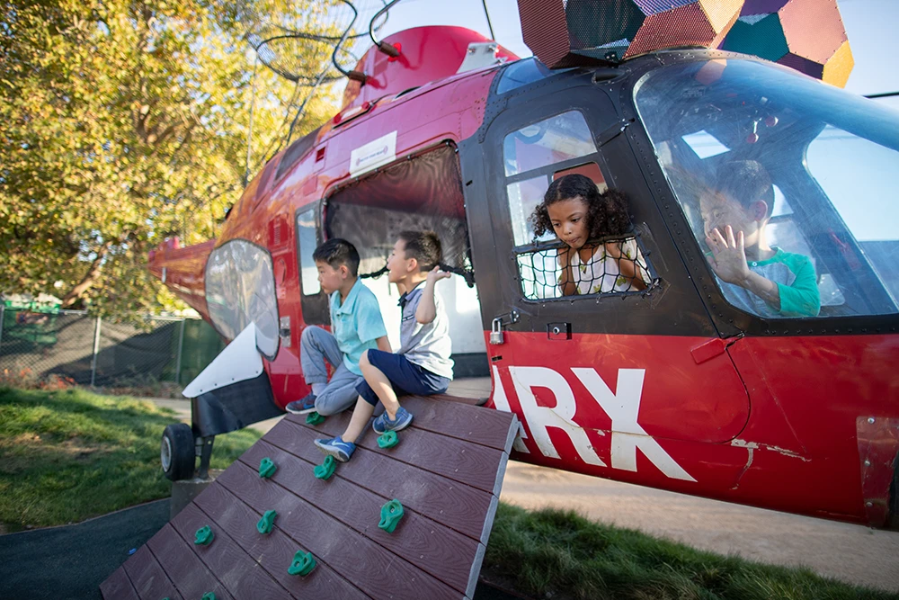 Cuatro niños juegan en un helicóptero real fuera de servicio llamado Ornitóptero.
