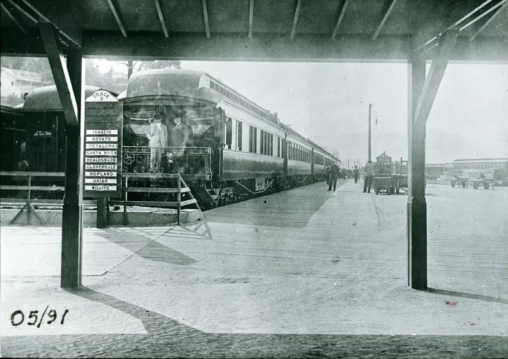 Sonoma County train depot; sign for Track 5 lists Ignacio, Novato, Petaluma, Santa Rosa, Healdsburg, Cloverdale, Hopland, Ukiah, and Willits. Northwestern Pacific observation car, handcarts and various railroad tracks.