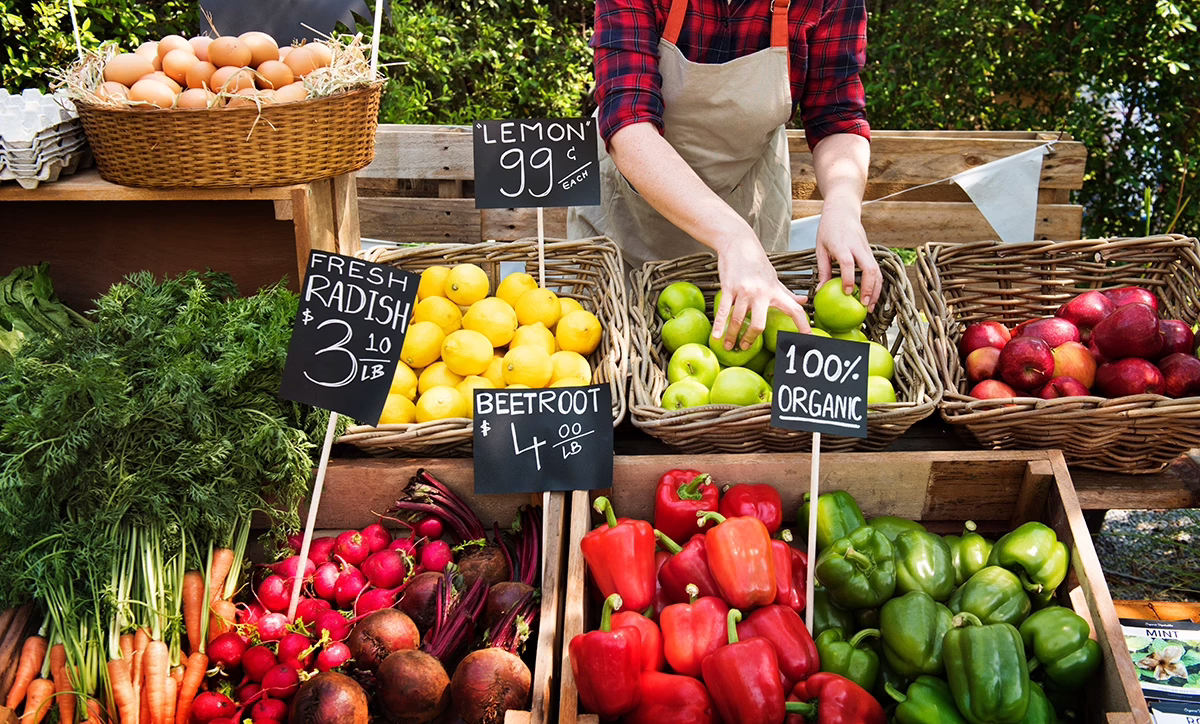A close up of a large Farmer's Market stand with baskets of fresh veggies; teaching children where food comes from concept