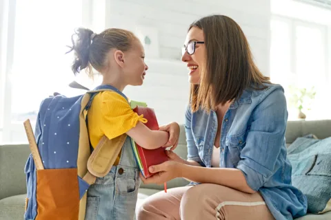 A mother and toddler smiling at each other, excited for the first day of school.