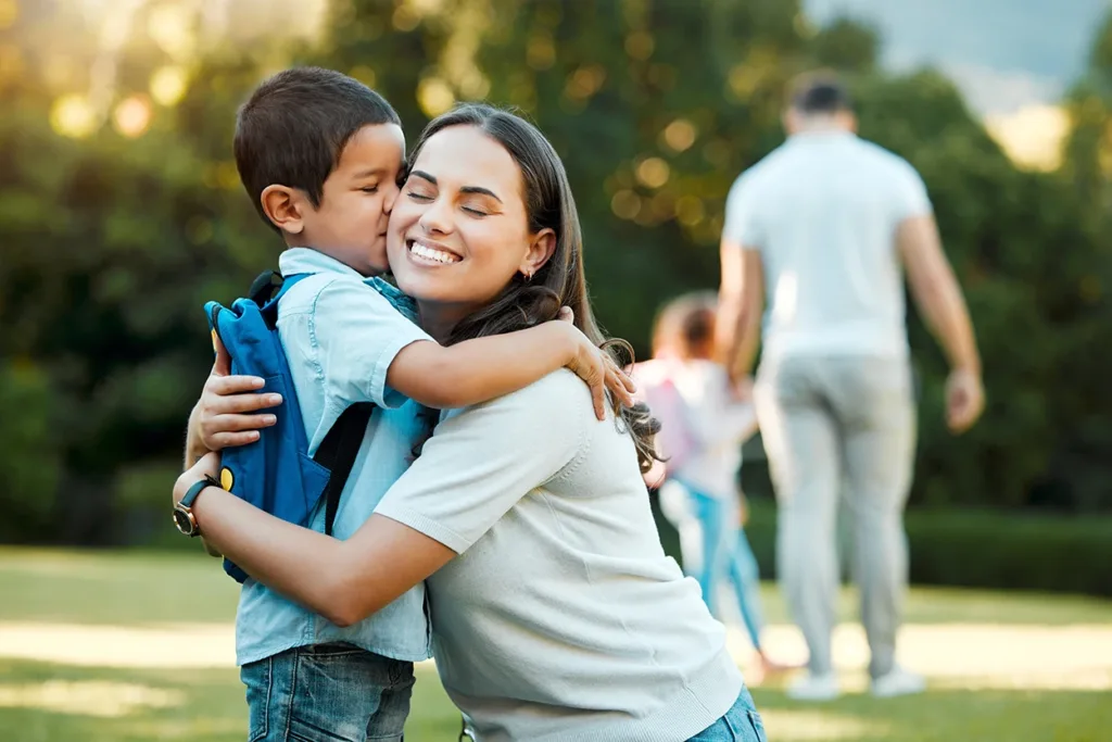 toddler kissing mom on the cheek on the first day of school at drop-off