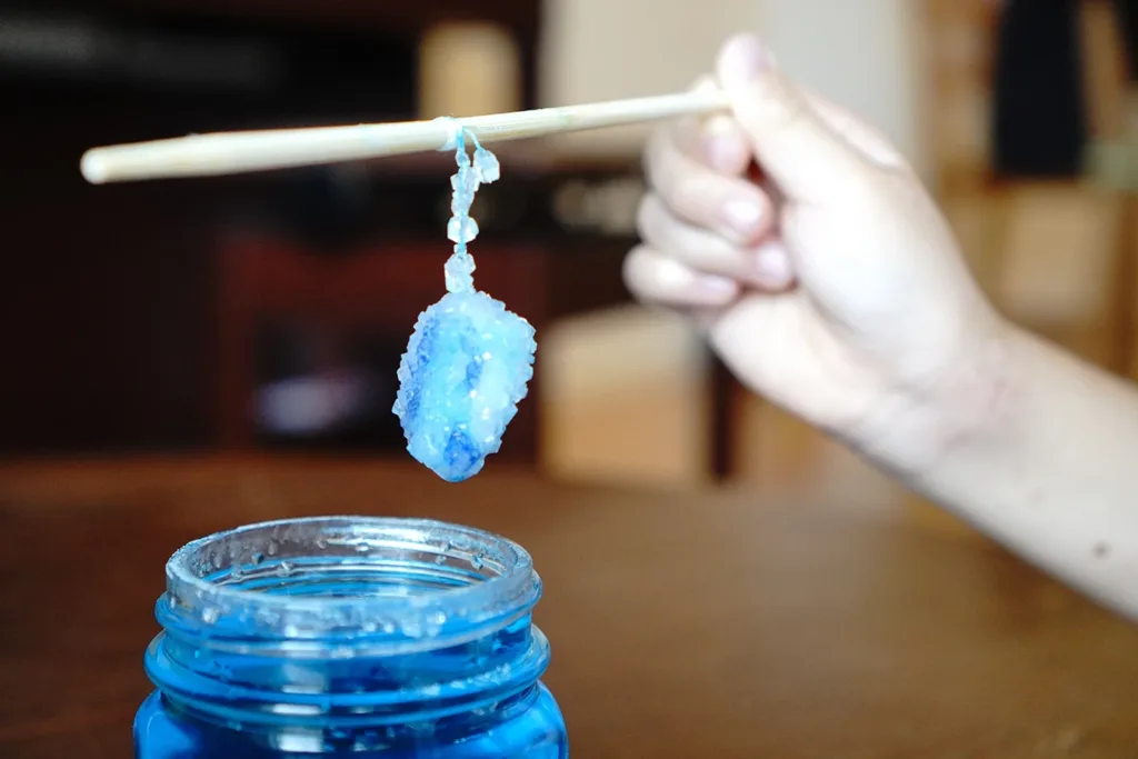 A child holding a stick with a Borax Crystals growing in it for a Halloween Science Experiments for Kids.
