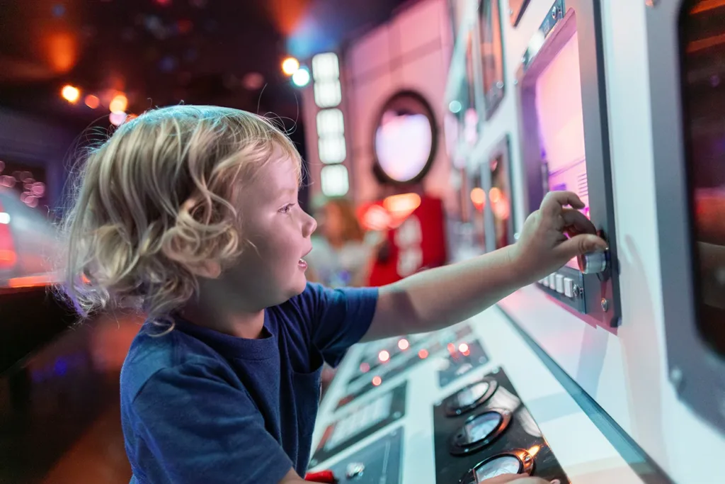 A young child playing with an interactive exhibit called the Space Odyssey for Galactic Explorers exhibit at the Children's Museum of Sonoma County