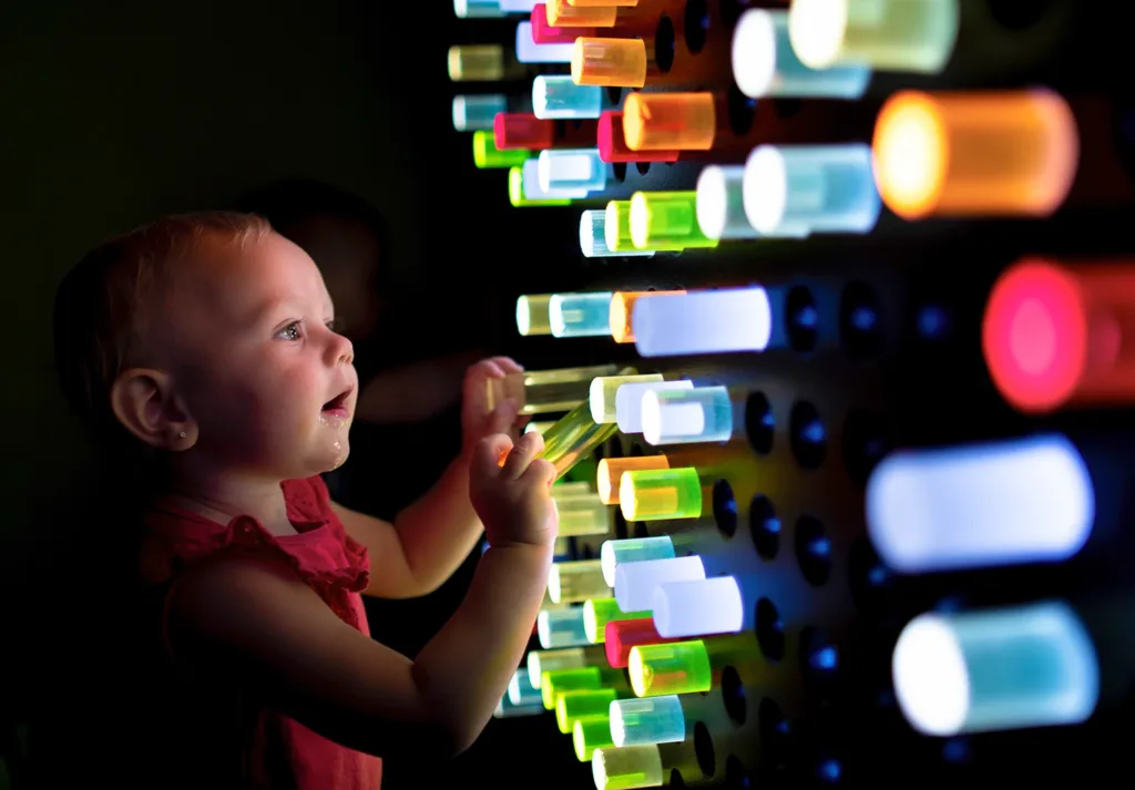 A young child playing with an interactive exhibit called the Light Peg Wall exhibit at the Children's Museum of Sonoma County
