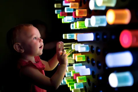 A young child playing with an interactive exhibit called the Light Peg Wall exhibit at the Children's Museum of Sonoma County