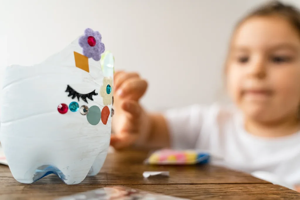 Actividad artística de reciclaje creativo para niños, ideas para actividades artísticas con botellas de plástico recicladas, la mitad inferior de una botella de plástico de refresco convertida en una pieza de arte decorativa.