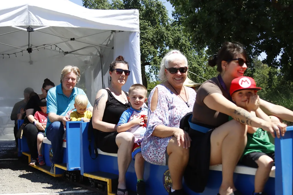 Children and caregivers riding a miniature train ride conducted by a Redwood Empire Live Steamers club member through a misting tent to help them stay cool. Picture taken at the 2025 Dino Trax event at the Children’s Museum of Sonoma County in Santa Rosa, CA.