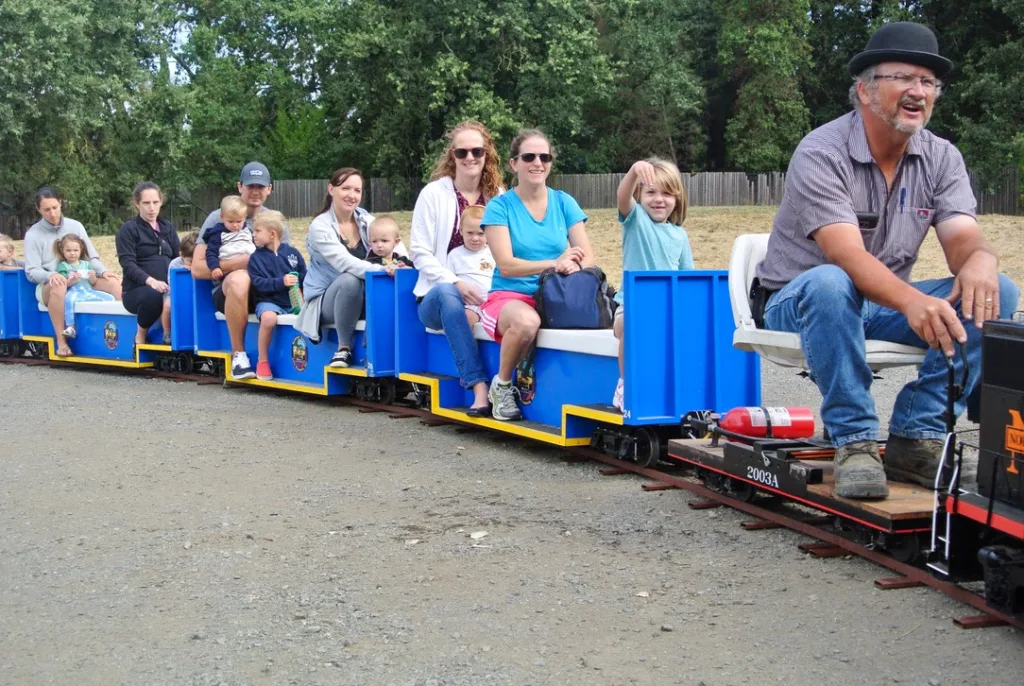 Children and caregivers riding a miniature train ride conducted by a Redwood Empire Live Steamers club member at the Children’s Museum of Sonoma County in Santa Rosa, CA.