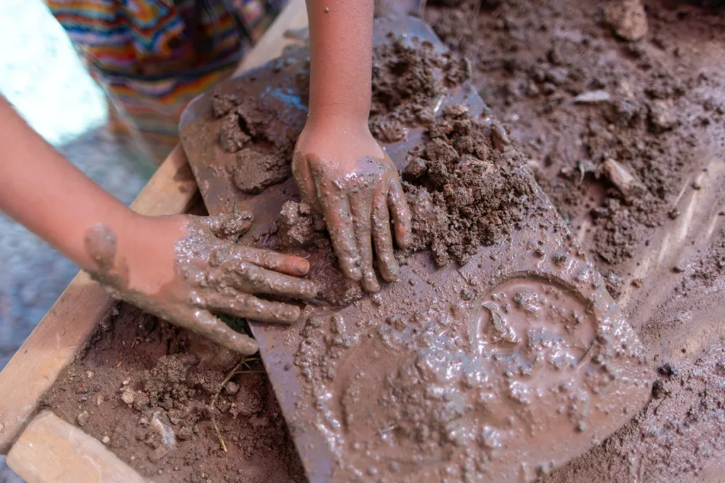 A young child packing mud into a cupcake backing sheet at the outdoor exhibit called Mud Lab at the Children’s Museum of Sonoma County.