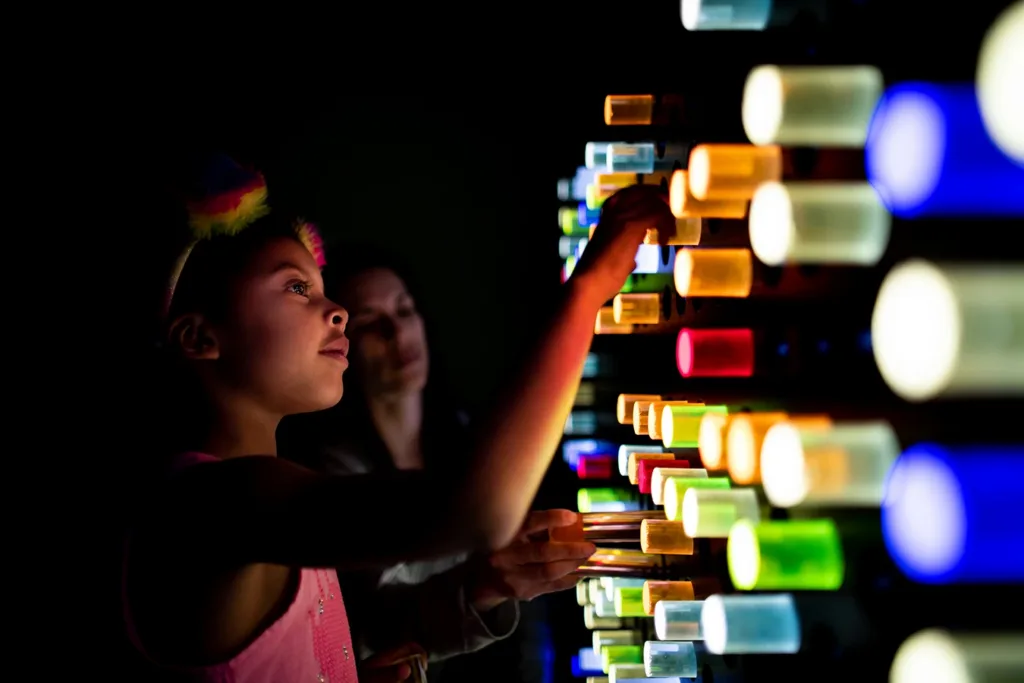 A young child learning about the science of light while playing at the Light Peg Wall exhibit at the Children’s Museum of Sonoma County in Santa Rosa, CA.