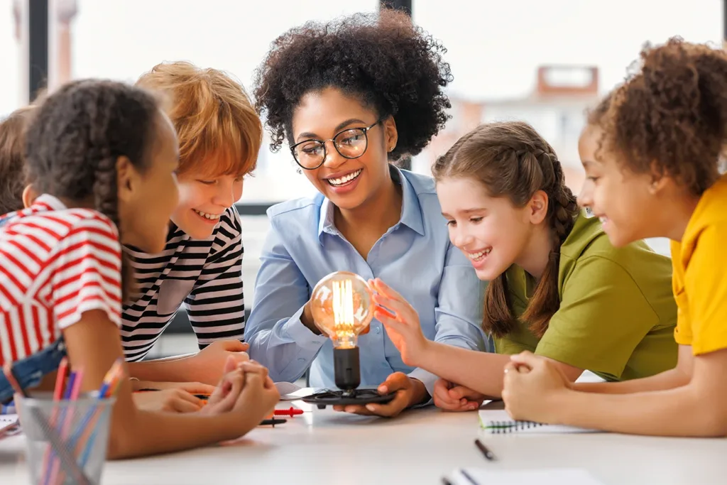 A teacher and multiple young students gathered around a light bulb as they learn about the science of light.
